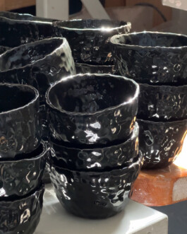 Finished ceramic cups with custom branding stacked in the sunshine.