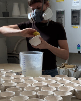 Eine Person wischt mit einem Schwamm über eine Tasse um diese vom Staub zu befreien.